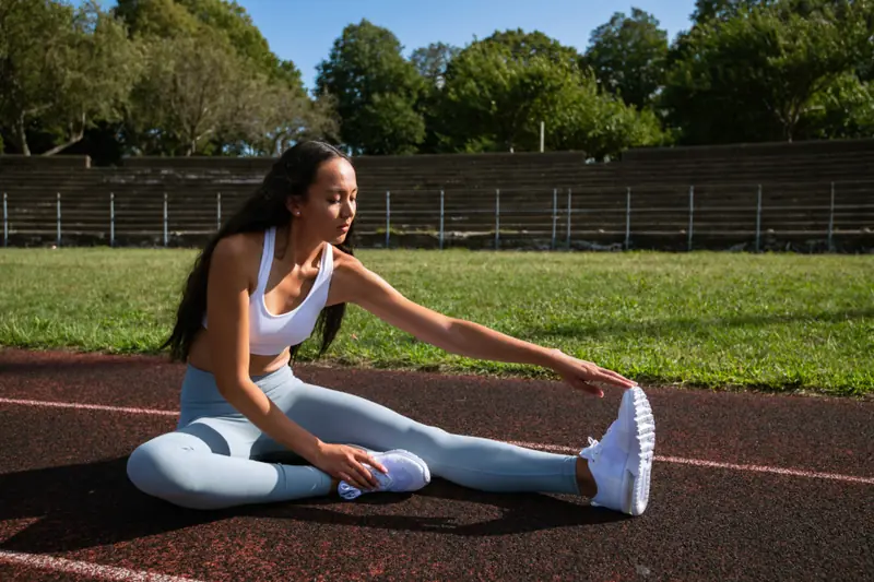 Femme qui s’étire sur une piste d’athlétisme
