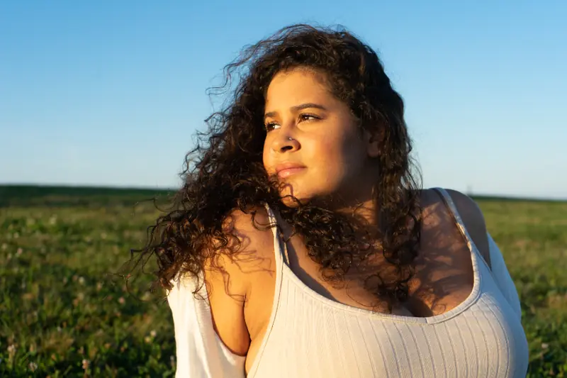 Femme aux cheveux bouclés dans un champ au soleil