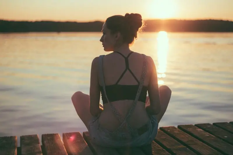 Femme qui médite face au soleil couchant