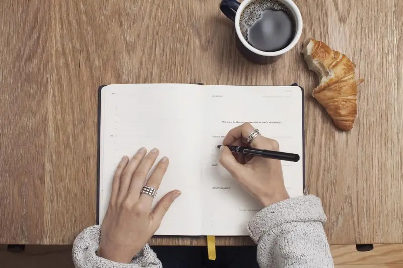 Carnet, café et croissant sur une table en bois