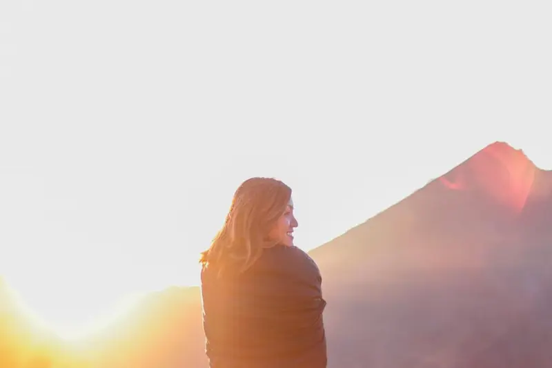 Femme face au soleil levant en montagne