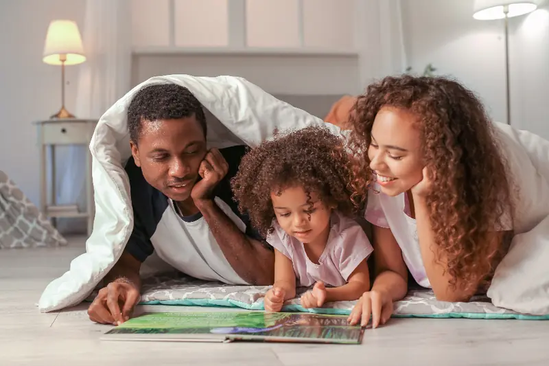 Parents et enfant qui lisent sous une couverture