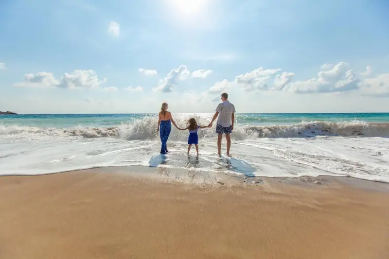 Famille qui marche main dans la main au bord de la mer