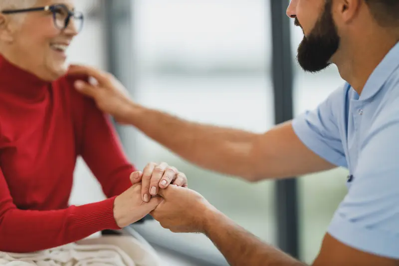 Femme souriante qui tient la main d’un proche