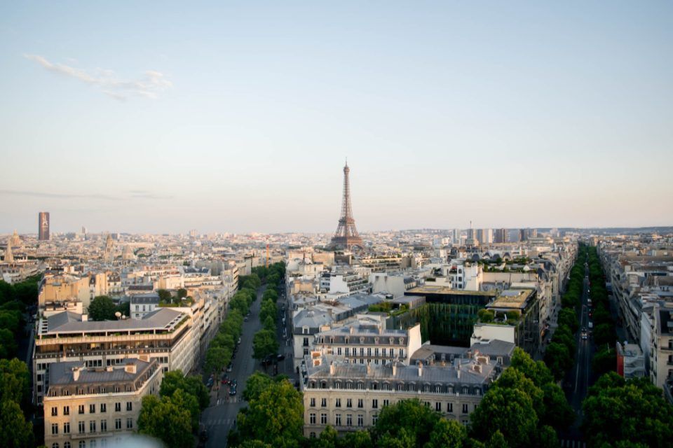 Vue aérienne des immeubles haussmanniens et des avenues arborées de Paris, la tour Eiffel à l’horizon
